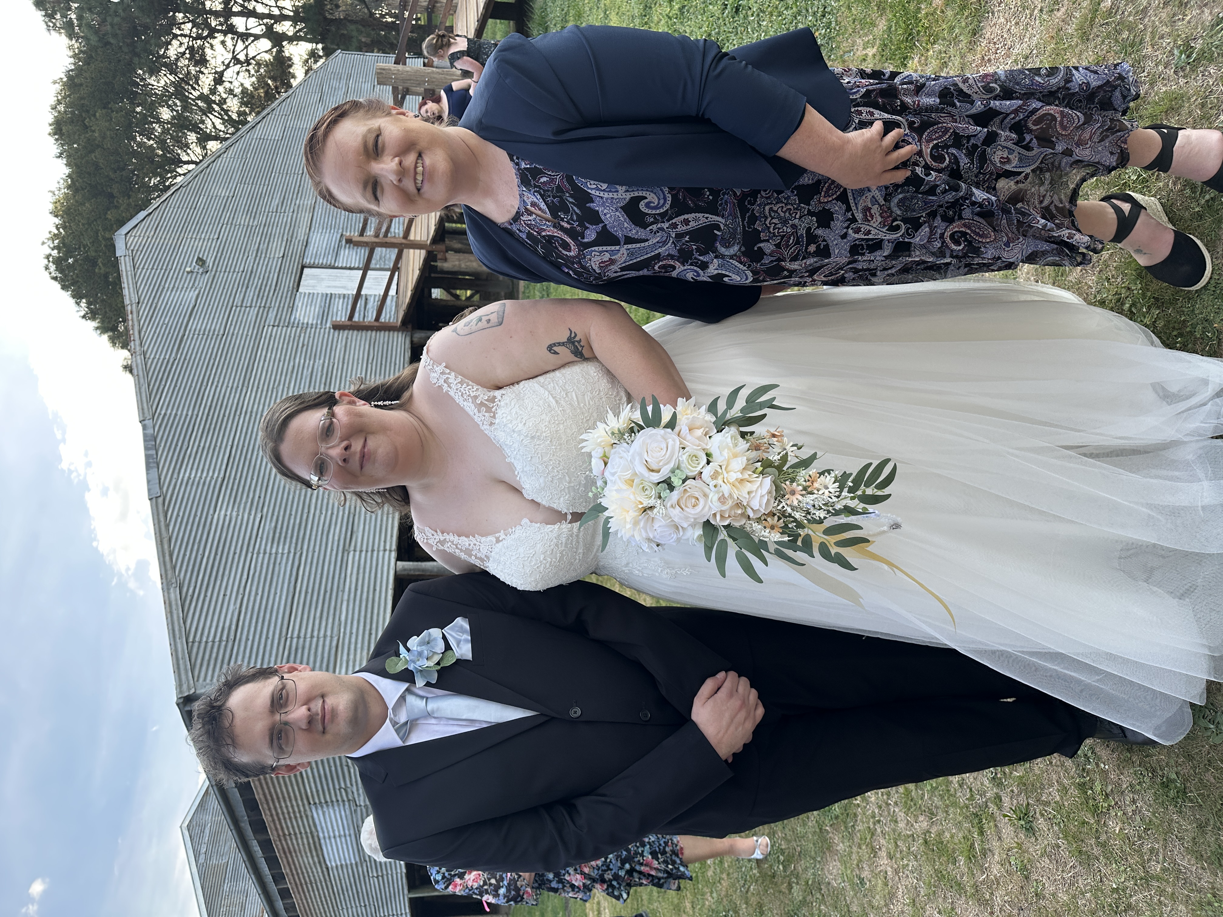 Allison Barker with a bride and groom at a rustic outdoor wedding